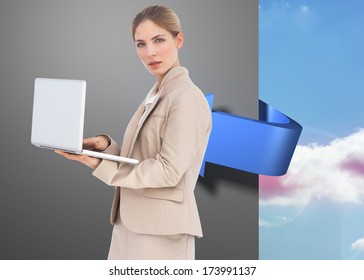 Businesswoman with a laptop against blue arrow pointing around a wall against sky - Shutterstock ID 173991137