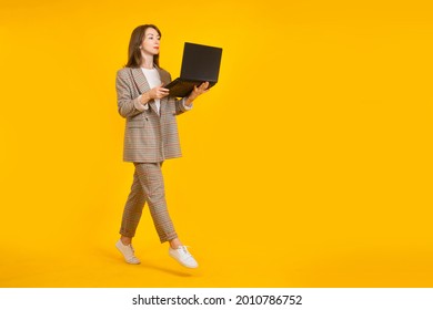 Businesswoman Laptop. Woman With Laptop On Yellow Background. Girl With Laptop In Business Suit. Businesswoman Uses Computer While Standing. Businesswoman In Plaid Suit. Bussines Software Concept.