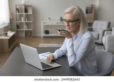 Businesswoman lead business talk on speakerphone use smartphone, provide information to client, record thoughts, use easy and comfortable method. Artificial intelligence, virtual assistant usage, tech - Powered by Shutterstock