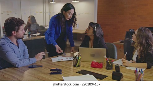 Businesswoman Leader Speaking With Team Colleagues. Senior Female Executive Communicating With Employees Inside Corporate Office At Night