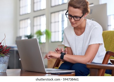 businesswoman looking at alerts notifications on smartwatch device in creative office - Powered by Shutterstock