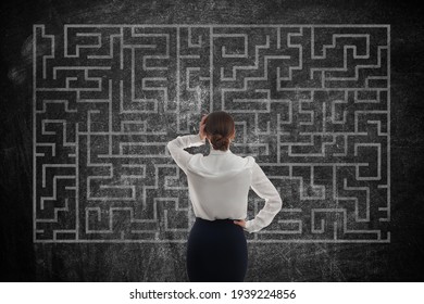 Businesswoman looking at chalkboard with illustration of maze - Shutterstock ID 1939224856
