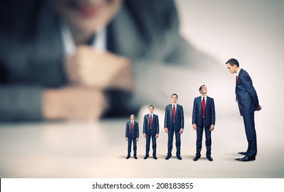 Businesswoman looking at miniature of business people of different sizes