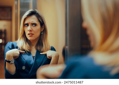 
Businesswoman Looking in the Mirror Feeling Insecure. Self-doubting manager having second thoughts suffering from impostor syndrome 
