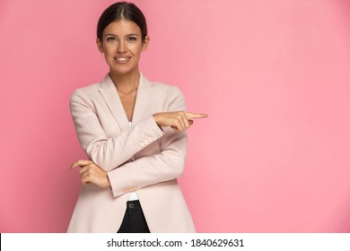 Businesswoman Looking One Way And Pointing The Other Against Pink Background