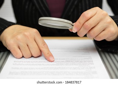 Businesswoman looking through a magnifying glass to contract