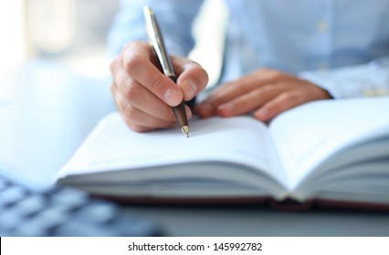 Businesswoman makes a note in notebook. 