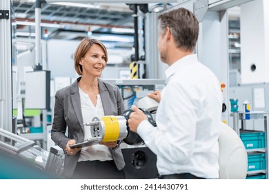 Businesswoman and man talking at assembly robot in a factory - Powered by Shutterstock