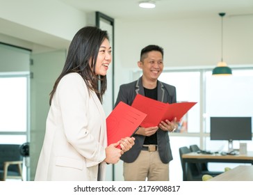 Businesswoman manager holding a file while talking and smiling, side view. Office training or giving briefing concept.