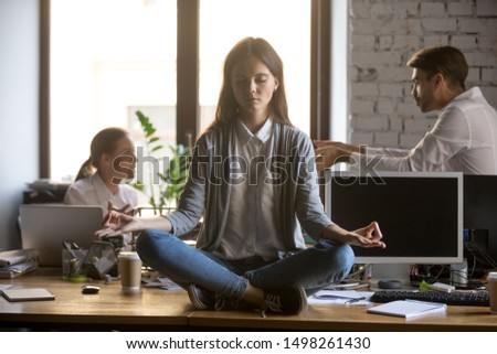 Businesswoman meditating at workplace, avoiding problem at work, ignoring annoying colleagues, female employee, intern sitting with closed eyes at office desk, keep calm in stressed situation