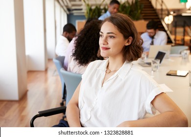 Businesswoman In Modern Office With Colleagues Meeting Around Table In Background