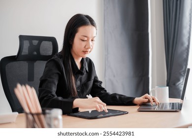 Businesswoman multitasking with laptop and tablet at a desk in a contemporary office environment. - Powered by Shutterstock