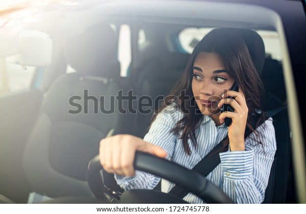 Businesswoman\
multitasking while driving, drinking coffee and talking on the\
phone. Distracted woman talking on her phone while driving. Woman\
Talking on Mobile while\
Driving