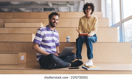 Businesswoman with notebook and businessman with laptop looking at camera. Business cooperation and teamwork. Caucasian colleagues on wooden benches in coworking office space. Modern successful people - Shutterstock ID 2192720351