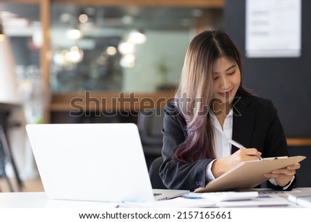 Businesswoman or office secretary working on paperwork is writing a monthly work diary.