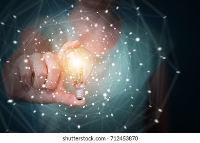 Businesswoman on blurred background holding a lighbulb with connections in her hand - Shutterstock ID 712453870