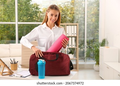 Businesswoman Packing Sports Stuff For Training Into Bag In Office