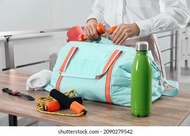 Businesswoman Packing Sports Stuff For Training Into Bag In Office, Closeup