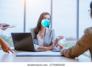 Businesswoman And Partner Business Team Work Meeting Are Discussing With New Strategy Business Project With Laptop And File Document At Office,she Wearing Face Mask To Protect  Virus .New Normal.