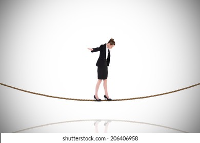 Businesswoman performing a balancing act on tightrope against white background with vignette