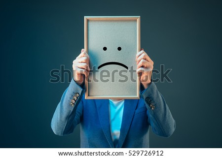 Businesswoman is pessimistic about her future in corporate business, holding printed sad smiley emoticon over her face Foto stock © 