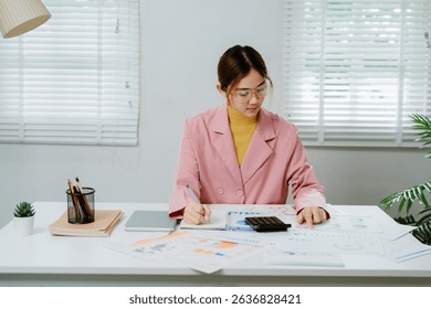 Businesswoman in pink suit is analyzing financial charts and calculating company expenses.