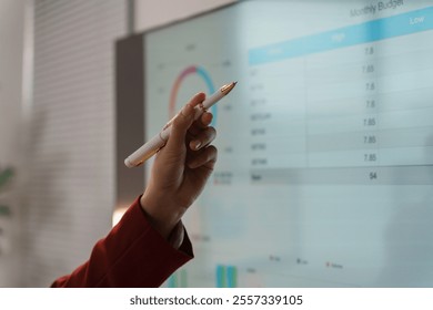 Businesswoman is pointing at a digital interactive whiteboard showing financial data during a presentation - Powered by Shutterstock