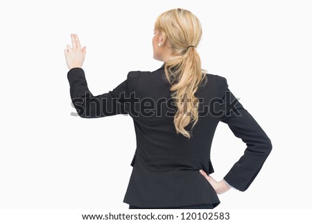 Businesswoman pointing something while standing and having her hand on the hip