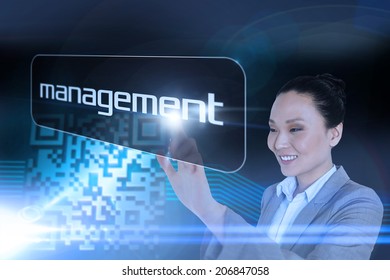 Businesswoman pointing to word management against shiny barcode on black background