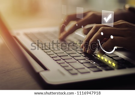 Businesswoman pressing smiley on keyboard laptop .Customer service evaluation concept.
