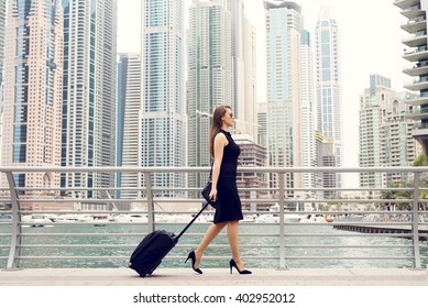 Businesswoman pulling a suitcase in a big city.