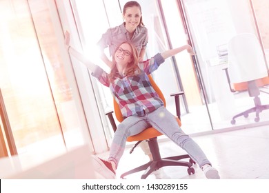 Businesswoman Pushing Colleague In Office Chair