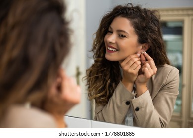 Businesswoman is  putting earrings while preparing for work.