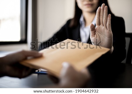 Businesswoman raised her hand to deny accepting a bribe from a business partner, a brown envelope containing a large number of dollar bills as money for bribery, a corruption concept. Foto stock © 