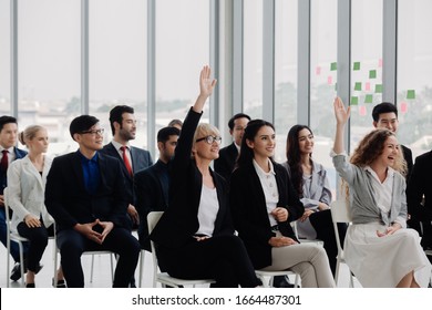 Businesswoman Raising Hand During Meeting In Office. Young People Sitting On Conference Together While One Man Raising His Hand