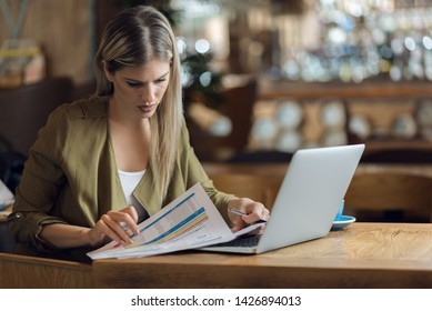 Businesswoman reading documents while working in a cafe - Shutterstock ID 1426894013