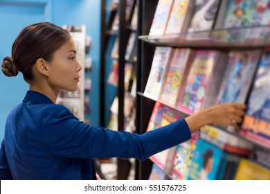 Businesswoman reading magazines at newsstand store of airport or train station. Asian woman shopping at bookstore.