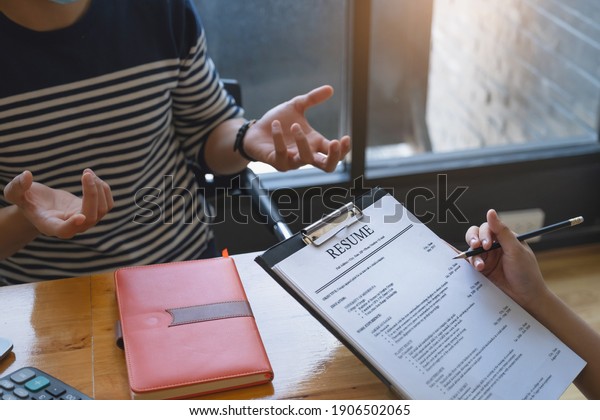 Businesswoman reading resume of man on\
document during an\
interview.