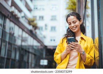 A  businesswoman reading something funny on her mobile phone on the street while going back home from work. Connected city worker. Close up of a young lady using a phone while on the street - Powered by Shutterstock