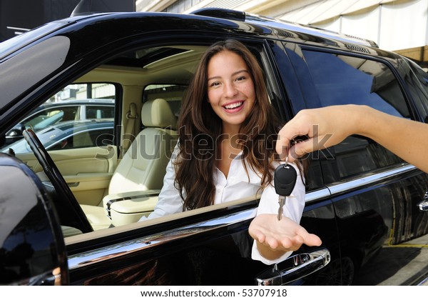 businesswoman receiving keys of her new status car\
from dealer