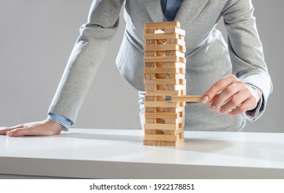 Empresaria quitando el bloque de madera de la torre sobre la mesa. Gestión del concepto de riesgos con juego de cajas de madera. Desarrollo empresarial y asistencia. Nuevo desafío y motivación de liderazgo.