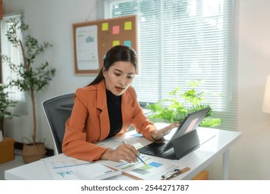 Businesswoman is reviewing financial data and having a video conference on her tablet in her bright home office - Powered by Shutterstock