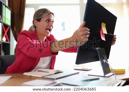 Businesswoman screaming hysterically at computer monitor in office. Shocked woman financial mistake bad news and online blackout