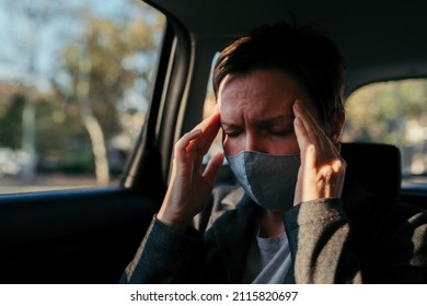 Businesswoman With Severe Headache Pain Symptoms And Protective Face Mask At The Backseat Of A Car, Selective Focus