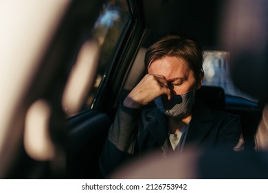 Businesswoman With Severe Headache Pain Symptoms And Protective Face Mask At The Backseat Of A Car, Selective Focus