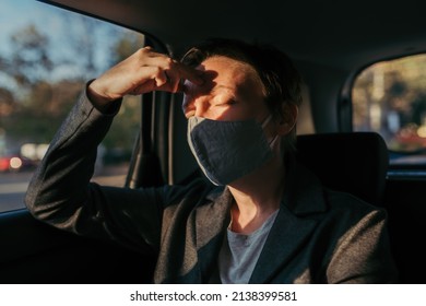 Businesswoman With Severe Headache Pain Symptoms And Protective Face Mask At The Backseat Of A Car, Selective Focus