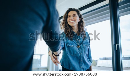Businesswoman shaking hands with a man in office boardroom. Employer shaking hands with job candidate for interview.