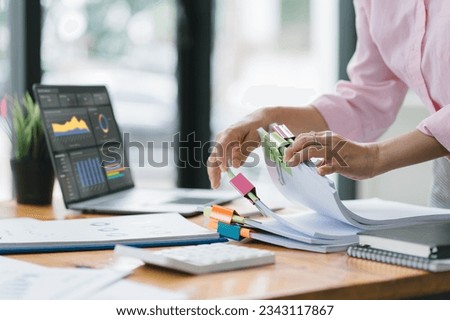 A businesswoman is sifting through stacks of paper files and folders that contain both incomplete and completed documents