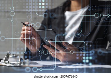 Businesswoman is signing the contract to create fin-tech start up for the conference and gain investments for innovative service. Checking the details at smartphone. Hologram tech graphs. - Shutterstock ID 2007676640