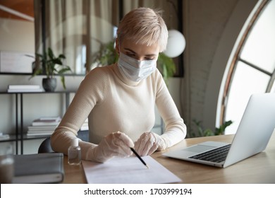 Businesswoman Sit At Desk In Office In Protective Face Mask And Rubber Gloves During Coronavirus Outbreak, Female Employee Work On Laptop Protect From Covid-19 Corona Virus Pandemic At Workplace